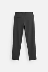 Pantalón negro de corte slim fit, confeccionado en tejido elástico. Cuenta con cintura elástica, bolsillos frontales y traseros de vivo. Cierre frontal con cremallera y botón.