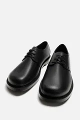 Zapato de vestir de cuero negro, tipo derby con cordones, punta redondeada y suela con ligero tacón.