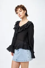 Blusa blanca de gasa con escote en V y volados en el cuello y las mangas largas. Se ata con lazos finos al frente.