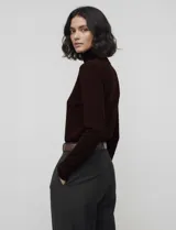 Polera de punto fino marca Nienty, color blanco, con cuello alto volcado y mangas largas con detalle de tajo en los puños.