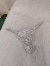 Microtanga de encaje color tostado con diseño floral y tiras ajustables.