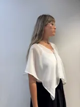 Poncho corto de gasa blanca, con escote amplio tipo barco y mangas amplias. Se lleva sobre otra prenda.