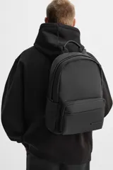 Mochila negra con acabado engomado, compartimento principal con cierre de cremallera, bolsillo interior con cierre, bolsillo frontal con cierre, bolsillos laterales planos, respaldo acolchado con sujeción para equipaje, asa de mano y dos asas de hombro ajustables y acolchadas.