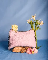 Cartera de cuero natural color rosa pálido, con forma de media luna y textura granulada. Posee una correa de cadena metálica plateada y cierre superior.