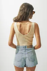 Top corto color crema, de tejido de punto acanalado, con escote en V y breteles anchos.