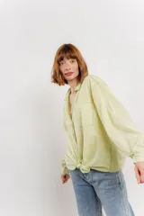 Camisa color crema de manga larga con cuello camisero y detalles de encaje en el escote. Se ata en la parte delantera.