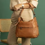 Cartera negra de cuero sintético con apertura superior y cierre con solapa. Tiene un bolsillo frontal con broche magnético y cierre, dos bolsillos internos y un bolsillo divisor en el forro. Incluye bolsillos laterales con cierre y correa larga regulable.