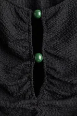 Top entallado corto de punto con textura suave, color negro. Tiene cuello redondo, abertura en V con cuentas de plástico y mangas cortas. Presenta costura fruncida en el frente para crear un efecto drapeado.