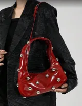 Bolso hobo verde militar con tachas plateadas, de tela suave y asa corta.