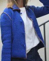 Saco tejido azul con cuello, manga larga y cierre frontal con lazos.