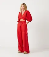 Conjunto de top corto con escote en V y mangas abullonadas, y pantalón palazzo con bolsillos cargo y lazo en la cintura, ambos en color rojo.