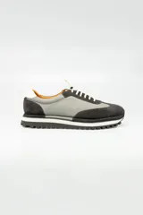 Championes de cuero italiano combinados en gris y negro, con cordones elásticos y cordones de algodón de repuesto. Suela de goma blanca con dibujo.