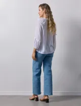 Blusa blanca de gasa bambula con cuello a la base y apertura central con botones. Apliques de crochet en la parte delantera y en las mangas ¾ con terminación fruncida.