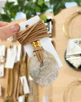 Collar con dije circular de nácar y cordón de cuero marrón.