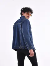 Campera de jean azul con cuello clásico, cierre frontal con botones metálicos, bolsillos con solapa abotonada en el pecho y bolsillos laterales.