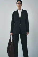 Blazer recta negra de Zara Woman Collection, con cuello solapa, manga larga con abertura y botones, bolsillos de plastrón en delantero, forro interior a tono y cierre frontal con botones.