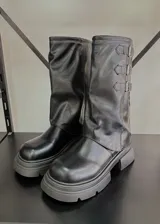 Botas negras de caña media con suela track y tres hebillas decorativas en el lateral.