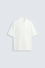 Camisa de calce relajado confeccionada en tejido jacquard de mezcla de algodón y viscosa. Presenta cuello bowling, manga corta, aberturas laterales en el bajo y cierre frontal con botones.