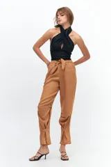 Pantalón de lino color marrón claro, con corte recto, cintura alta con lazo ajustable, elástico en la parte trasera y presillas en las piernas.