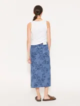 Pollera midi de denim celeste con estampado de limones y hojas en azul oscuro. Tiene corte recto, tiro alto y abertura frontal.