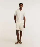 Camisa de manga corta color crema con bordado floral texturizado, cuello solapa y abotonadura frontal.