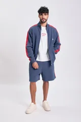 Short deportivo de tela de algodón, color azul marino, con franjas laterales rojas. Tiene cintura elástica y corte holgado.
