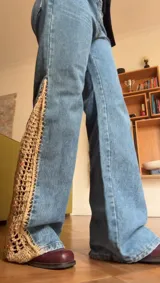 Pantalón de jean azul con crochet hecho a mano y detalles de pedrería en los laterales inferiores.