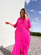 Vestido camisero midi de lino color fucsia, con cuello camisero, mangas 3/4 y cierre frontal con botones.