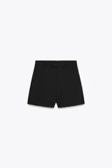 Shorts de tiro alto color negro, con trabillas en la cintura, bolsillos laterales y cierre frontal con cremallera y ganchos metálicos.