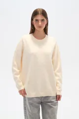 Sweater color crema, de corte holgado, con cuello redondo y mostacillas decorativas.