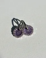 Par de aros colgantes con dije circular de resina color lila con glitter y strass plateados en el borde. El arito es de acero quirúrgico.