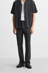 Pantalón negro de corte recto, confeccionado en tejido de mezcla de algodón y lino. Presenta cintura elástica, bolsillos laterales y traseros.
