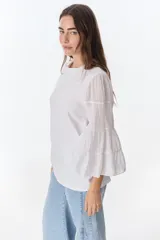 Blusa blanca de algodón con mangas largas acampanadas con volados.