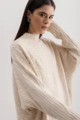 Sweater color beige de punto con cuello alto y diseño geométrico en relieve.