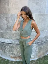 Pantalón verde de lino, de corte recto y tiro alto, con bolsillos laterales y cierre frontal con botón y cremallera.