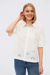 Camisa blanca de algodón con bordado calado de flores, cuello camisero, corte recto y mangas cortas.