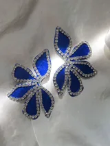 Par de aros con forma de flor azul de terciopelo, contorneada con strass y cierre a presión de acero inoxidable.