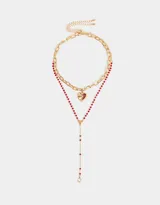 Set de dos collares dorados: uno con cadena de eslabones gruesos y dije de corazón esmaltado en rojo, y otro con cadena de cuentas rojas y dije de strass.