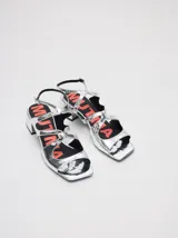 Sandalias de cuero charol color borgoña con tiras finas, taco cuadrado bajo y cierre con hebilla en el tobillo. Interior con estampado del logo de la marca en color naranja.