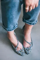 Zapato de tacón con estampado animal print gris y dorado, con puntera fina, talón descubierto y pulsera con hebilla lateral. Tacón ancho de 7 cm y suela de cuero.