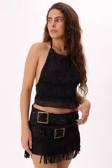 Minifalda negra de gamuza sintética con flecos en el ruedo y doble cinturón con hebillas metálicas.