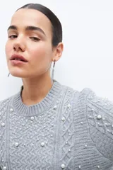 Sweater gris de tejido de punto con trenzas y perlas sintéticas.