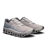 Championes de running On Cloudmonster Void, color gris con detalles en celeste y blanco. Presentan suela con tecnología CloudTec y diseño con perforaciones hexagonales.