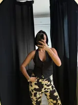 Chaleco negro con escote halter y cierre frontal con botones.