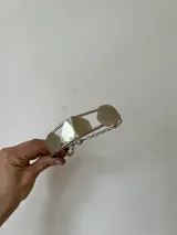 Gargantilla doble plateada con cadena de eslabones y tres piezas irregulares: una color cobre, una plateada y una gris.