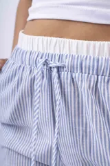 Pantalón de tela a rayas verticales celestes y blancas, con corte amplio, cintura elástica y cordón ajustable.