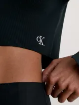 Cárdigan cropped negro de punto de canalé elástico con cierre de corchetes y logo CK bordado en el bajo.