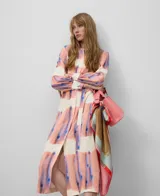 Vestido camisero midi con estampado abstracto en tonos rosa, azul y blanco. Tiene cuello camisero, mangas largas con puños, cinturón de lazo y bolsillos laterales.