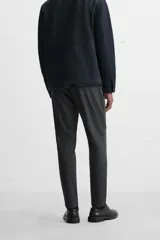 Pantalón negro de corte slim fit, confeccionado en tejido elástico. Cuenta con cintura elástica, bolsillos frontales y traseros de vivo. Cierre frontal con cremallera y botón.