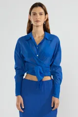 Camisa azul de manga larga con lazo en la cintura y botones nacarados.